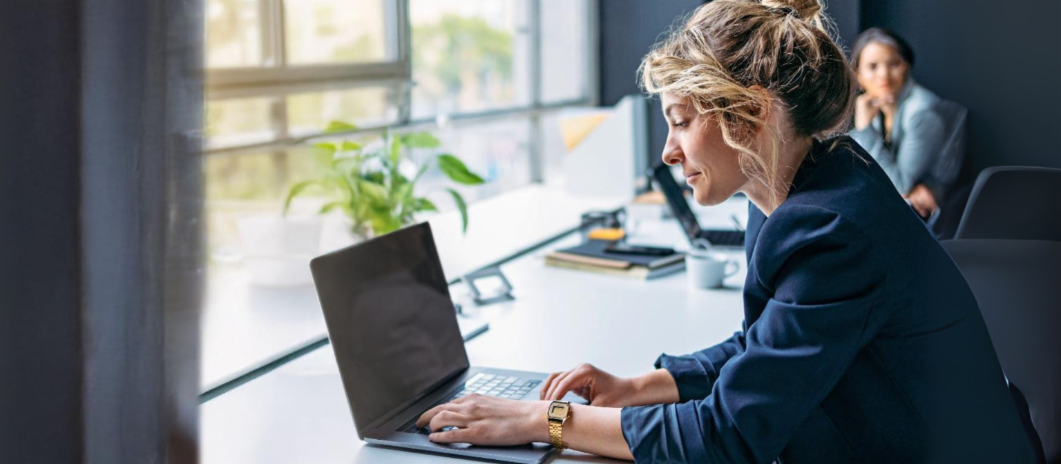Ung kvinde arbejder på en bærbar computer på et moderne kontor.