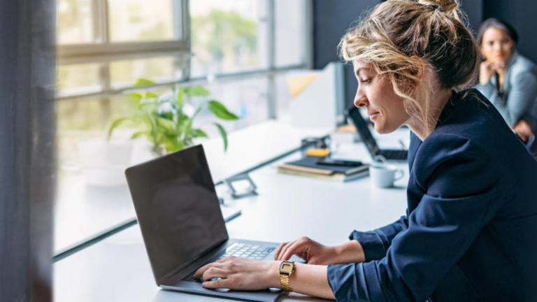 Ung kvinde arbejder på en bærbar computer på et moderne kontor.