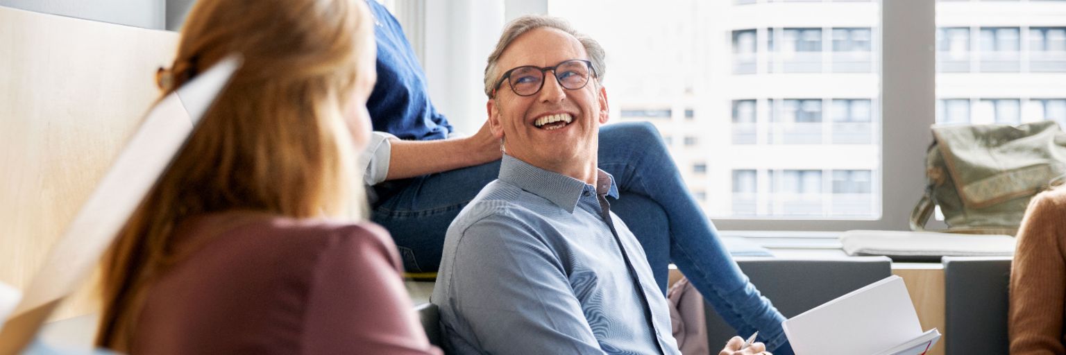 EOS-medarbejdere sidder i et moderne kontor og holder et møde, mens de tager noter.