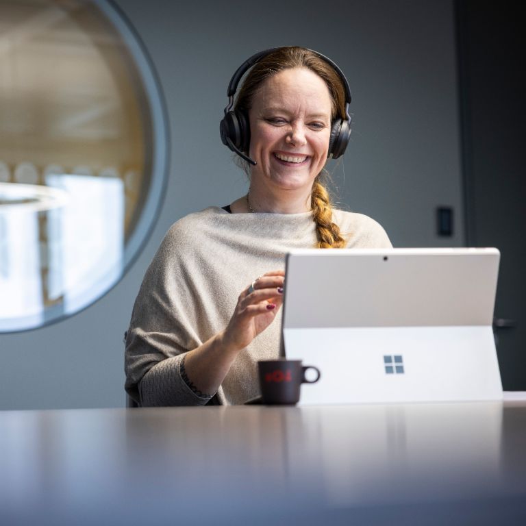 En EOS-medarbejder bærer et headset og ses smile, mens han samtaler med en digital modpart.