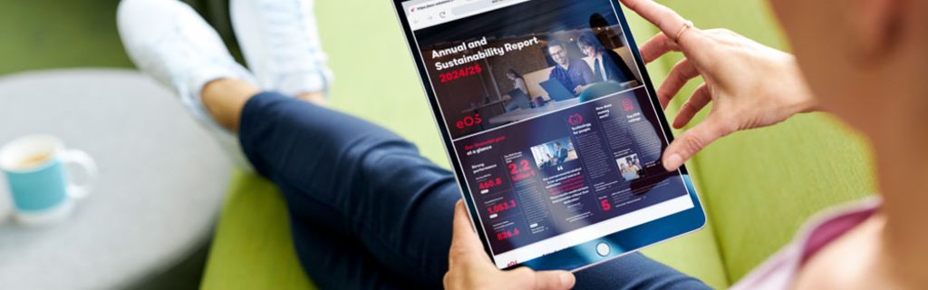 Person på grøn sofa, der ser EOS Årsrapport og Bæredygtighedsrapport 2024/25 på en tablet
