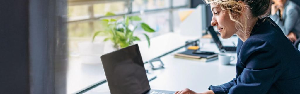 Ung kvinde arbejder på en bærbar computer på et moderne kontor.