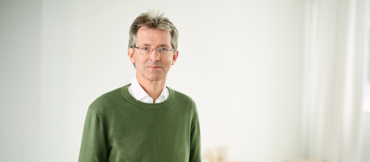 Justus Hecking-Veltman, CFO iført grøn pullover og hvid skjorte, står i et lyst lokale.