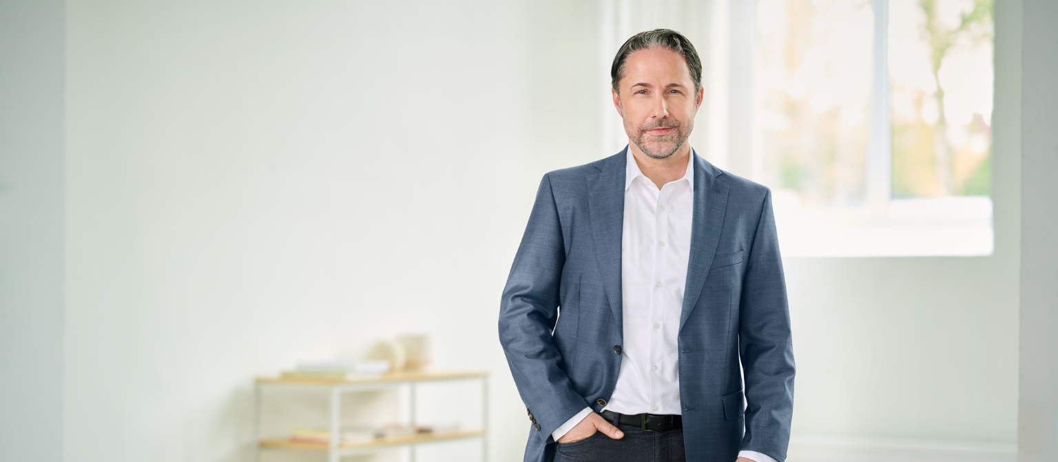 Marwin Ramcke, CEO, står i et lyst rum iført blåt jakkesæt og højre hånd i bukselommen. 