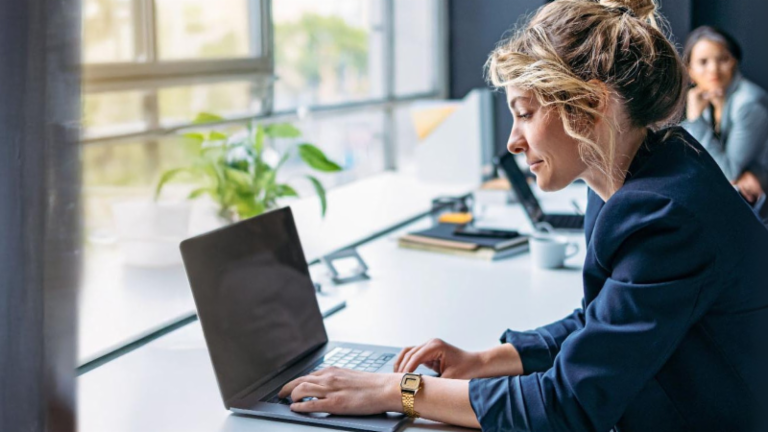Ung kvinde arbejder på en bærbar computer på et moderne kontor.