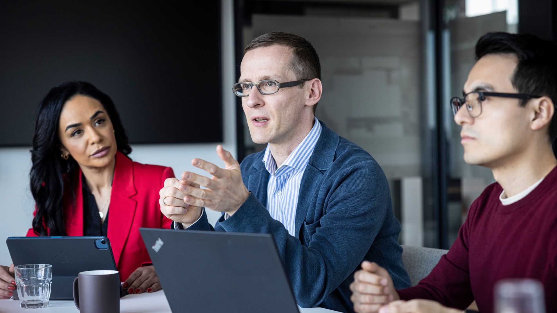 Tre personer fører en samtale på et kontor.