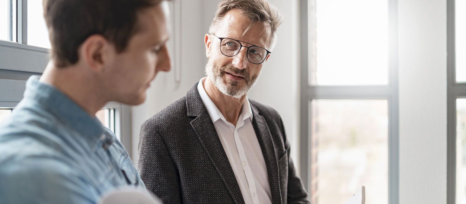 To mænd på et kontor diskuterer resultaterne af EOS Groups studie "European Payment Practices 2025" om digitalisering i fordringsstyring.