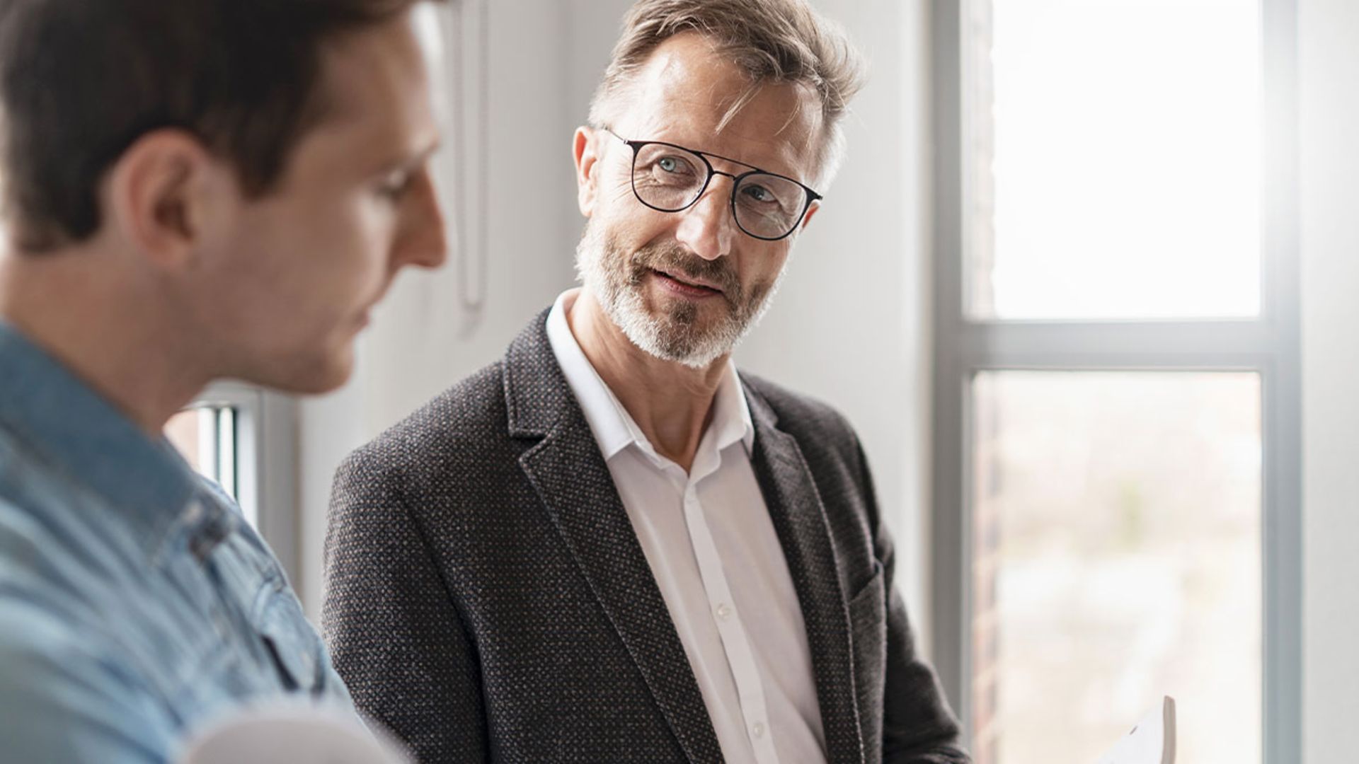 To mænd på et kontor diskuterer resultaterne af EOS Groups studie "European Payment Practices 2025" om digitalisering i fordringsstyring.